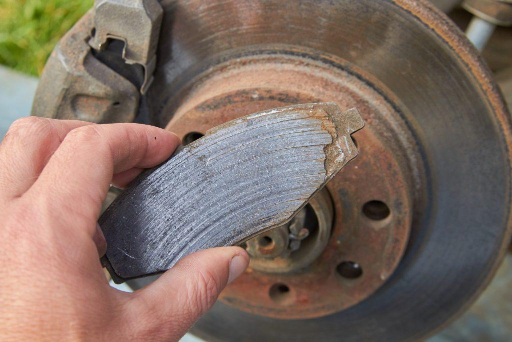 image of a hand holding a worn out brake pad