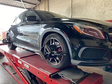 Black Mercedes sedan on alignment rack for alignment service