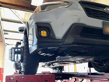 White Subaru SUV on alignment rack undergoing alignment service