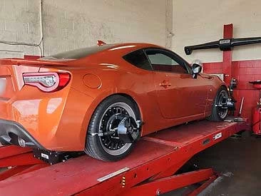Red Scion on alignment rack for alignment service