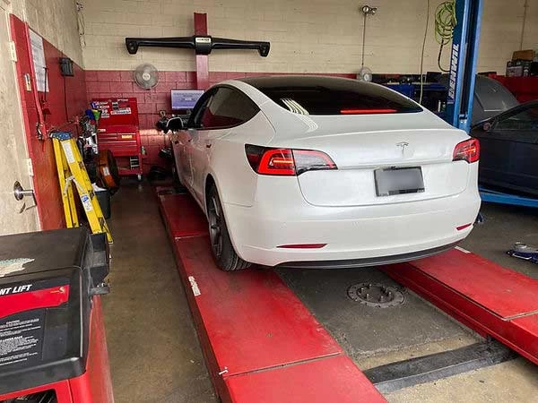 White Tesla on alignment rack for precision alignment with radar machine