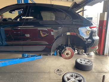  Black Subaru hatchback, rear wheels removed, rusty rear rotors