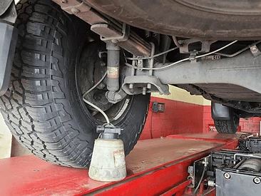 Brake bleeder connected to the rear driver caliper on a rack.