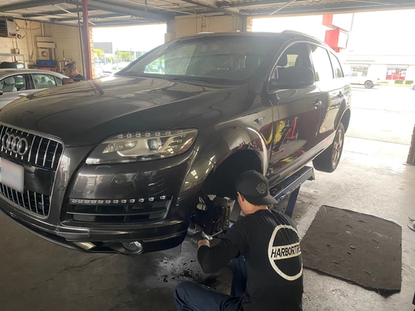 Dark grey Audi SUV on scissor lift, front driver's tire removed for brake replacement