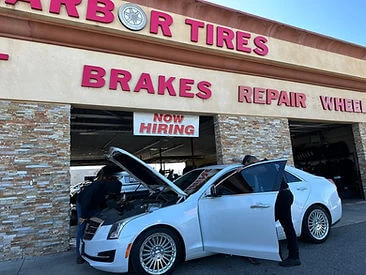 White sedan with open front hood, mechanic performing diagnostics