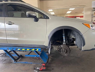 Tan SUV with a wheel removed on a scissor lift