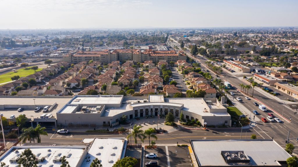 Aerial view of Stanton, California, showcasing residential neighborhoods, busy streets, and commercial buildings under a clear sky.